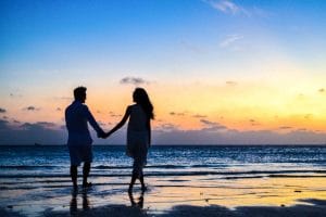 Beach honeymoon couple holding hands walking on beach